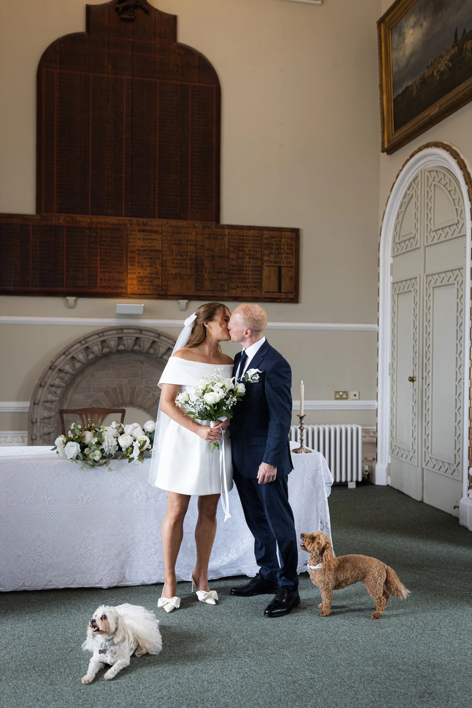 Edward and Emily sharing a kiss with their two dogs beside them at Arundel Town Hall — Sussex