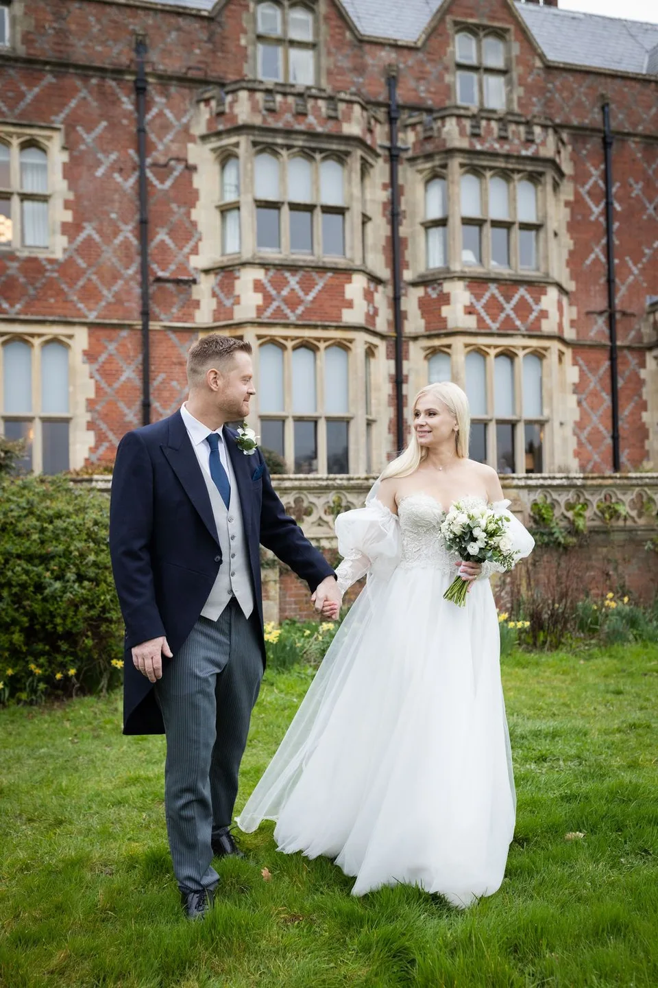 Vira and David holding hands in the gardens outside Horsted Place — Sussex