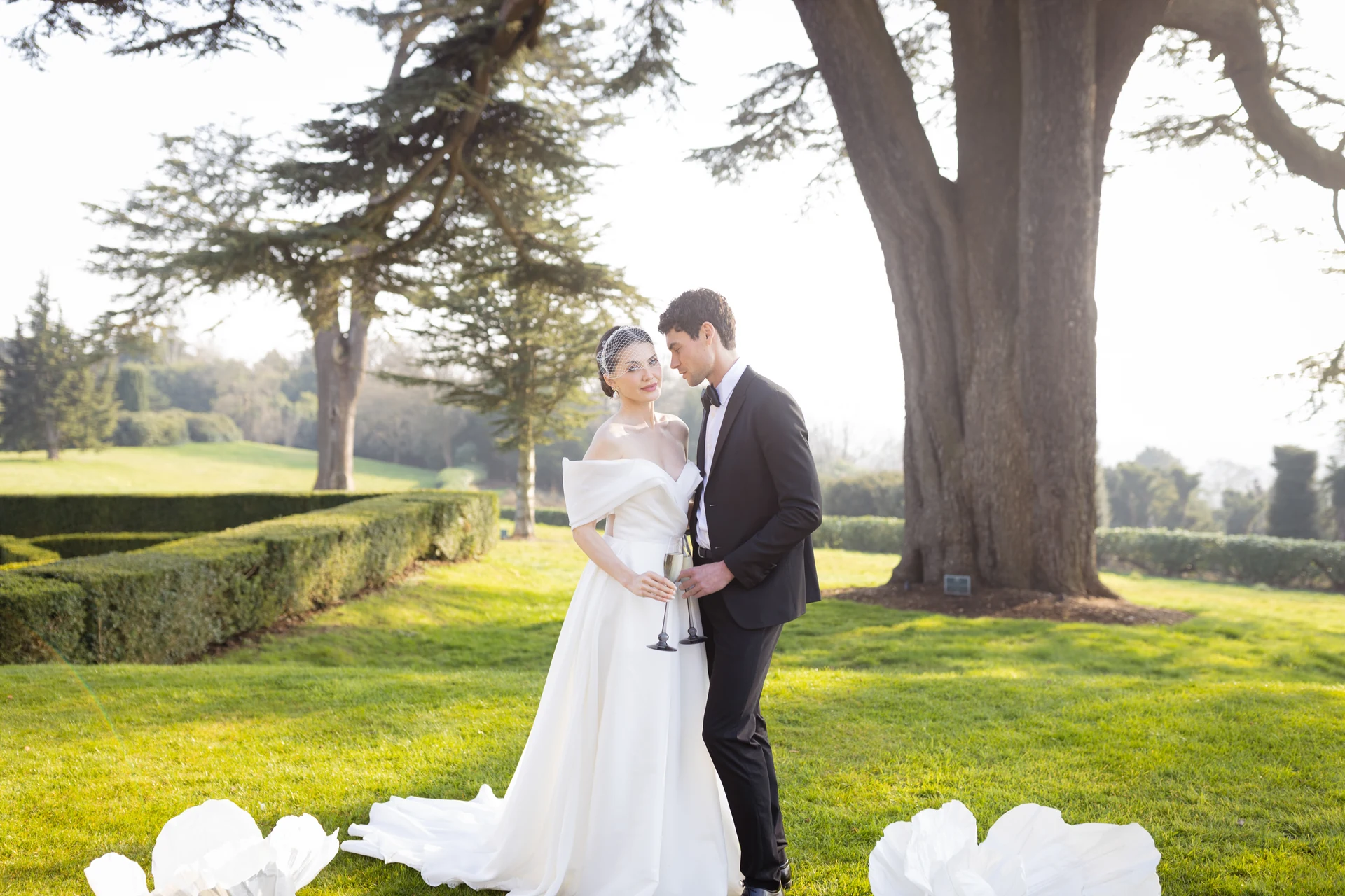 Pen and Joe holding champagne glasses beneath a tree at Hedsor House — Buckinghamshire