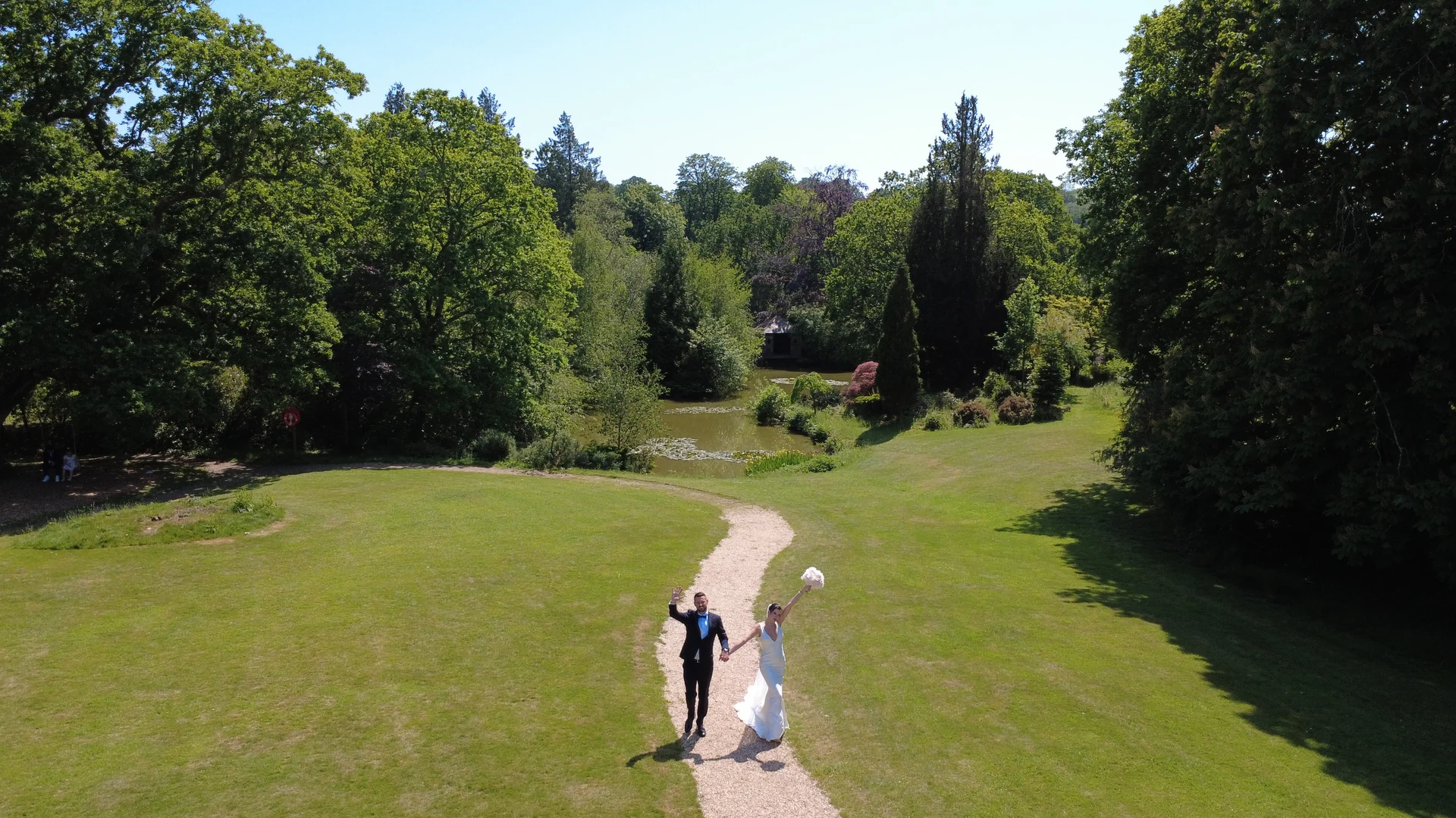 Jen and Stu holding hands in an aerial wedding photograph of The Ravenswood gardens — Sussex